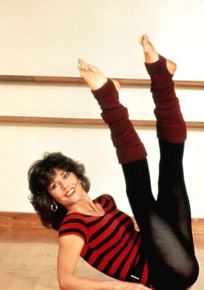 Jane Fonda in leg warmers and a striped leotard at a ballet barre