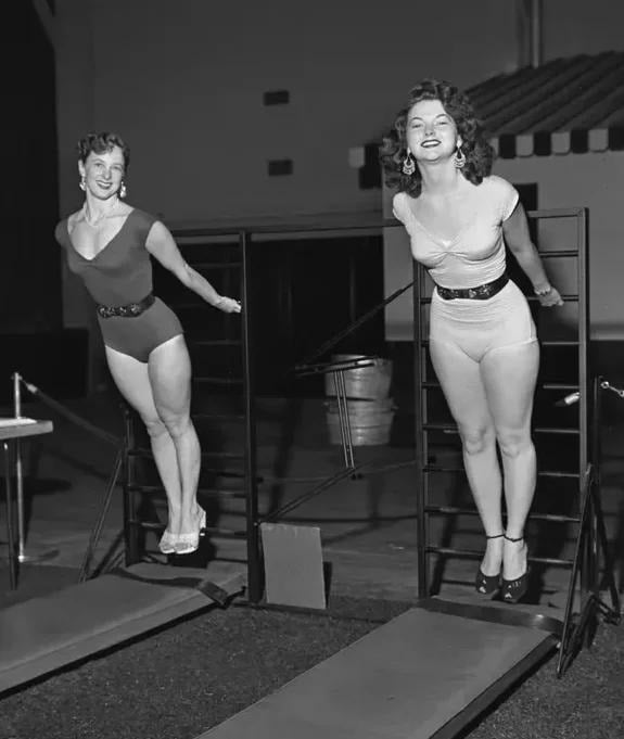 Two women exercising on a gym ladder, in black and white