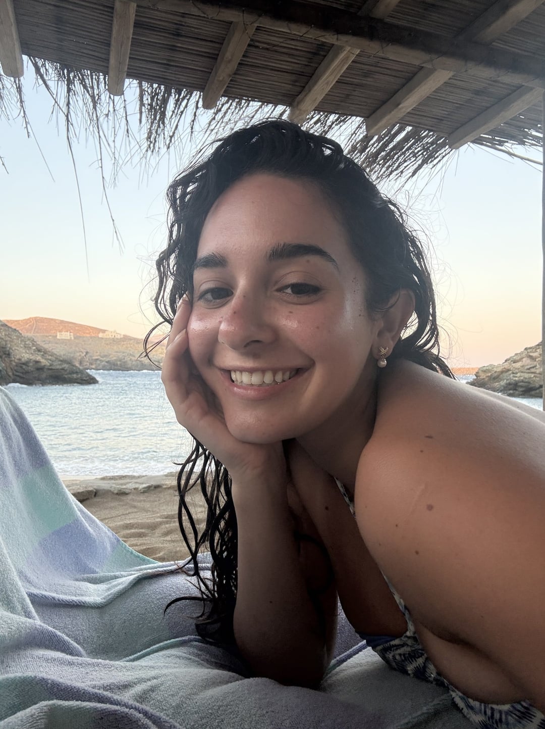 A smiling woman resting on a beach towel