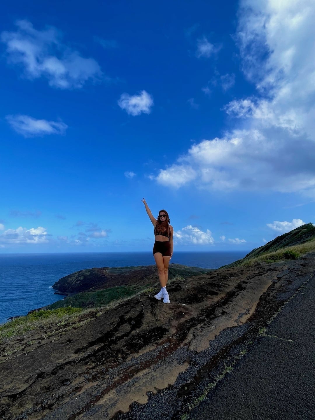 A woman on a rocky clifftop under a bright blue sky