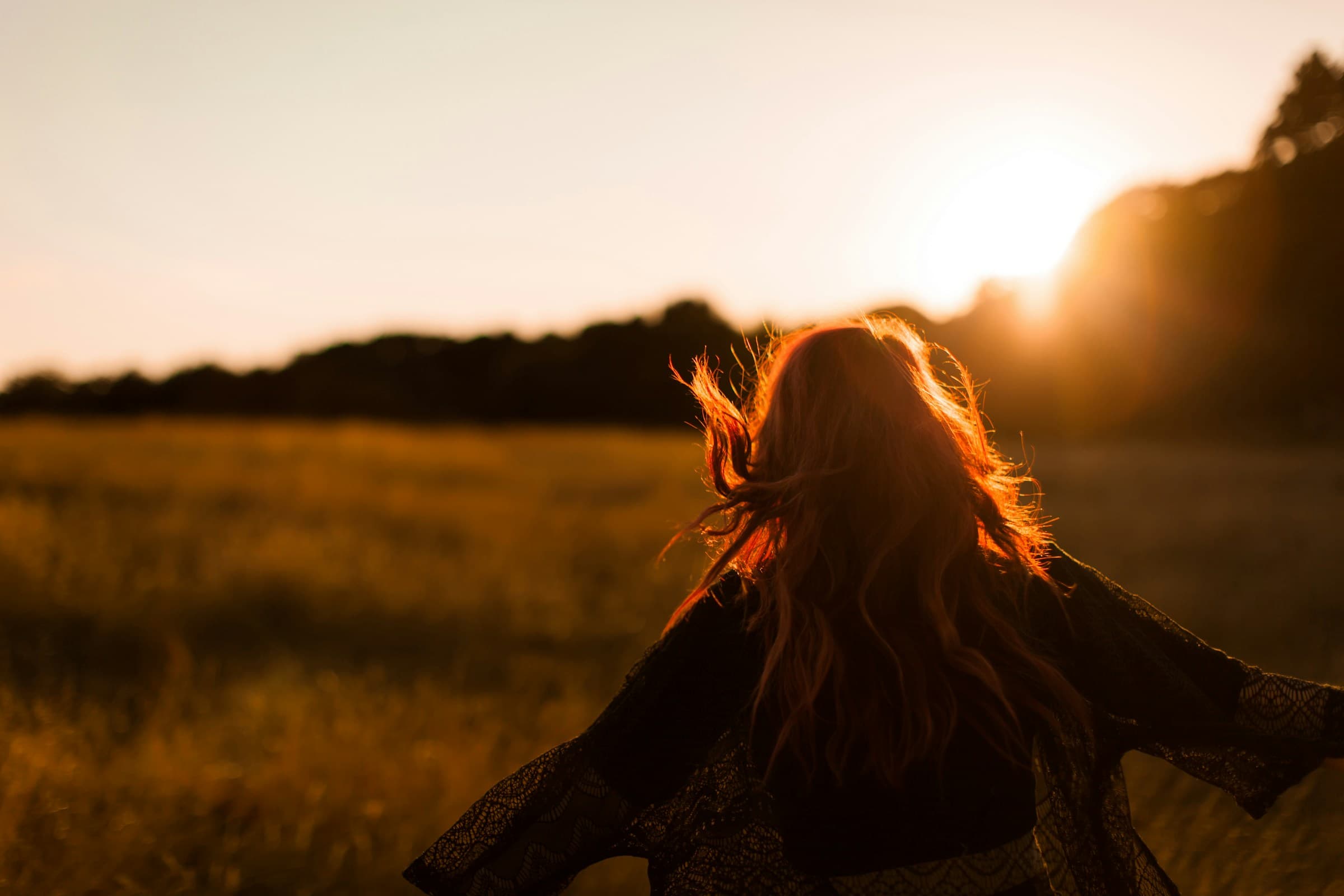 Woman with her arms open in a golden field at sunset